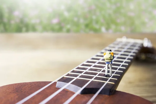 Musik und Reisekonzept von Miniatur-Backpacker auf der Ukulele — Stockfoto