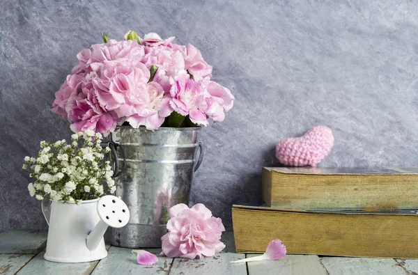 Flores de clavel rosa en cubo de zinc y libro sobre madera vieja — Foto de Stock