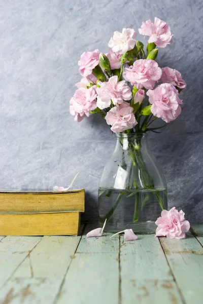 Fleurs oeillets roses en bouteille transparente sur vieux bois — Photo