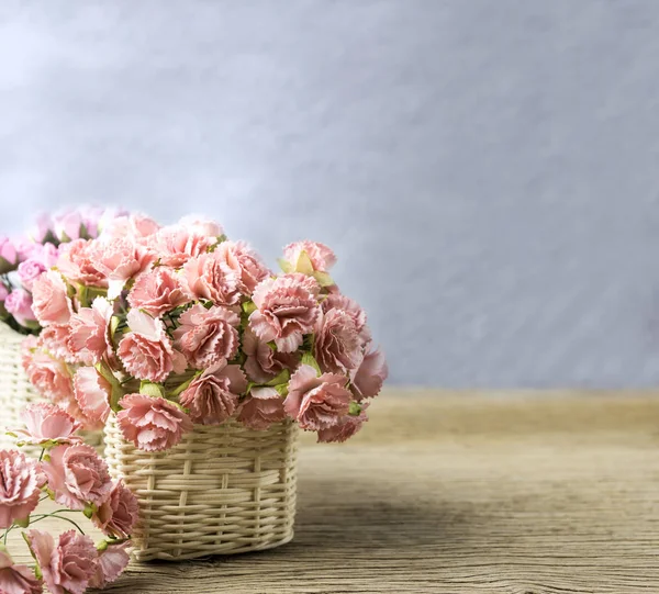 Paper carnation and rose flowers in basket on old wood with copy space — Stock Photo, Image