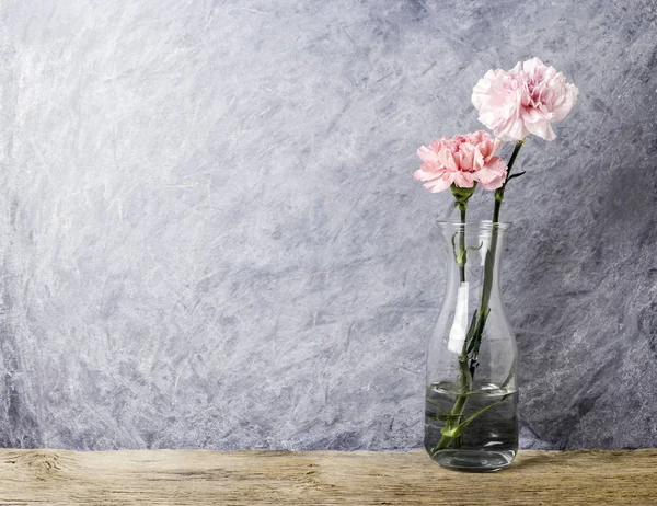 Pink carnation flowers in clear bottle — Stock Photo, Image