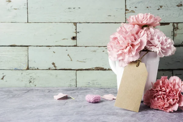 空白の茶色の紙タグと心の白いカップでピンクのカーネーションの花 — ストック写真