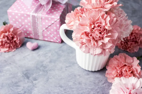 Conceito de dia das mães de flor de cravo rosa em copo branco e caixa de presente — Fotografia de Stock