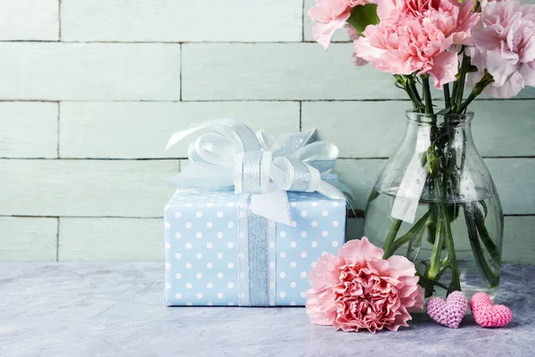 Concepto del día de las madres de flores de clavel rosa en botella clara y caja de regalo y corazón — Foto de Stock