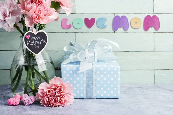 Mothers day concept of pink carnation flowers in clear bottle and gift box and heart — Stock Photo, Image