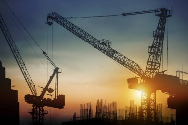 Siluet inşaat alanında gün batımında Vinçler ile