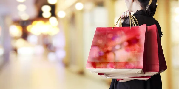 Jovem segurando saco de compras vermelho na loja de departamento — Fotografia de Stock