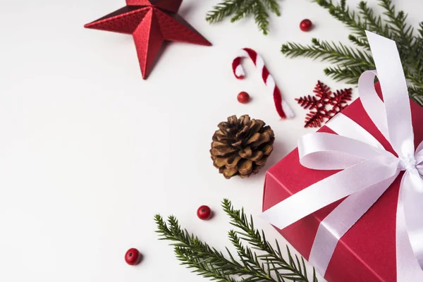 Χριστούγεννα και νέο έτος διακόσμηση του δώρου και φύλλα πευκόξυλου και κουκουνάρι σε φόντο λευκό χαρτί με αντίγραφο χώρου — Φωτογραφία Αρχείου