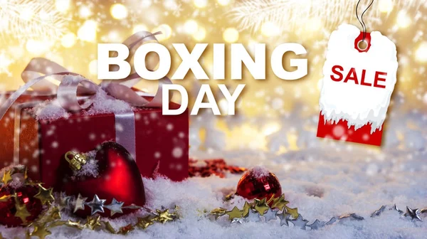 Concepto de la venta del día de boxeo de la caja de regalo roja en la nieve con fondo bokeh —  Fotos de Stock