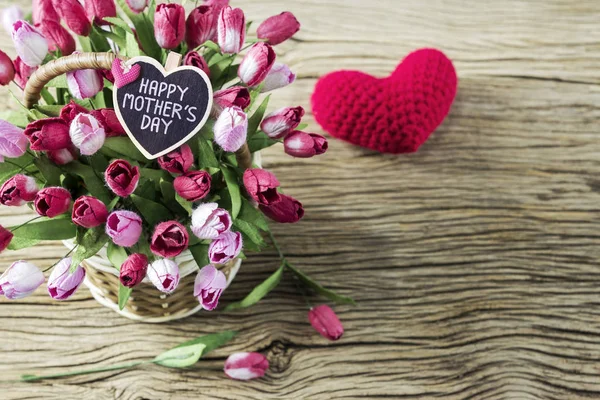 Feliz día de las madres de flores de tulipán rosa y rojo en canasta de madera con corazón rojo sobre fondo de madera — Foto de Stock