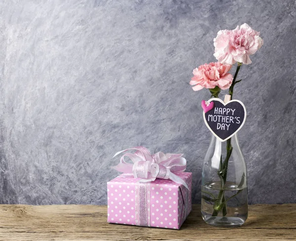 クリアなボトル、ギフト ボックスのピンク カーネーション花の母親日コンセプト — ストック写真