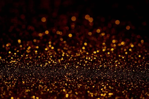 Abstract dark golden glitter background with shining light and soft bokeh, festive colors — Stock Photo, Image