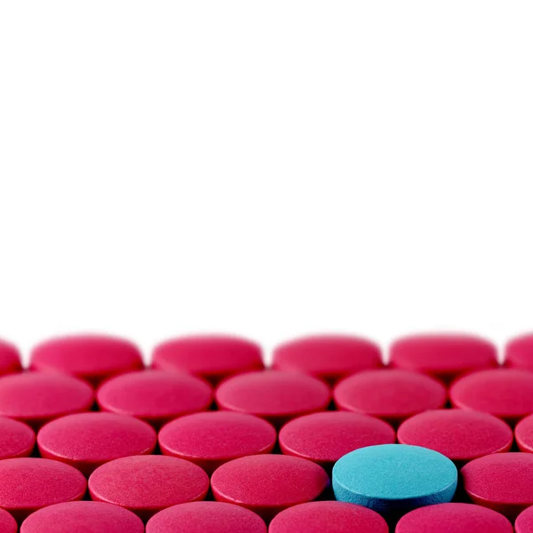 Comprimido azul entre pílulas vermelhas no fundo branco — Fotografia de Stock