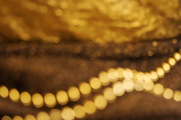 Ouro castanho brilhante desfocado férias abstratas luzes no fundo escuro. Fundo de Natal festivo dourado. Abstrato twinkled fundo brilhante com bokeh desfocado luzes de cor de ouro . — Fotografia de Stock