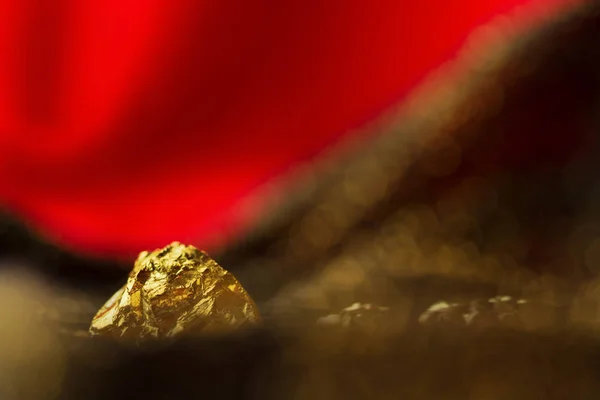 Nugget dourado no fundo macio vermelho com luzes de brilho — Fotografia de Stock