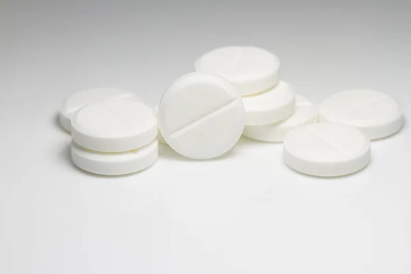 Pílulas médicas brancas em fundo branco com sombras e luz suave — Fotografia de Stock