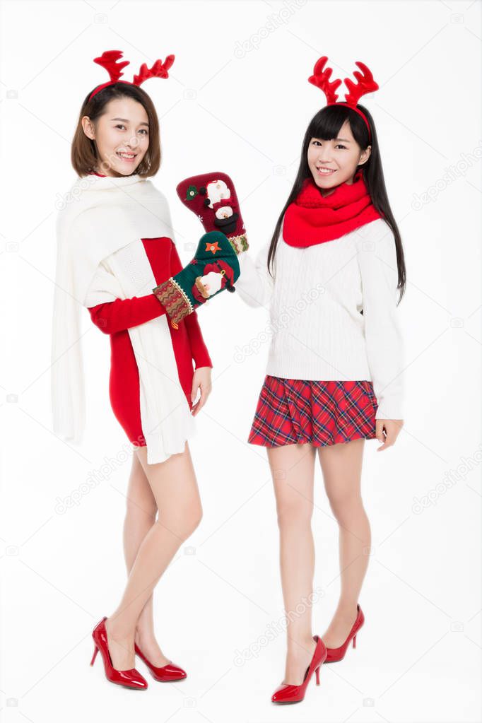 two young females holding christmas stockings smiling to th camera against white background.