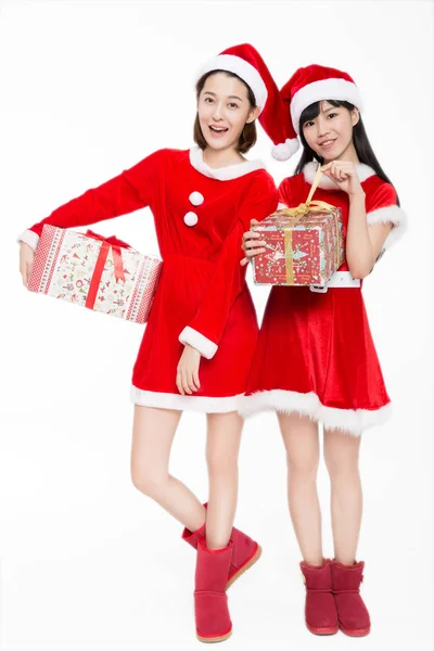 Dwie Młode Kobiety Kostiumach Mikołaja Prezentami Świątecznymi Uśmiechnięte Kamery Białe — Zdjęcie stockowe