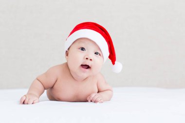 Noel Baba şapkası takan tatlı bebek yatakta yatıyor, Noel konsepti..