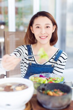 Restoran stoklarında yemek yiyen mutlu bir kadın.