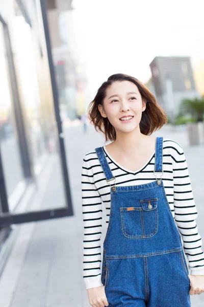 中国山东省 一名身穿蓝色牛仔裤工作服的年轻女子探索商业区的街道 — 图库照片