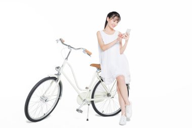 Akıllı telefon kullanan güzel bir kadın. Bisiklete yaslanmış, stüdyo fotoğrafı..