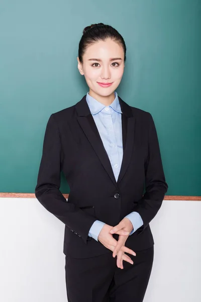 Portret van vrouwelijke leraar wijzend naar schoolbord. — Stockfoto