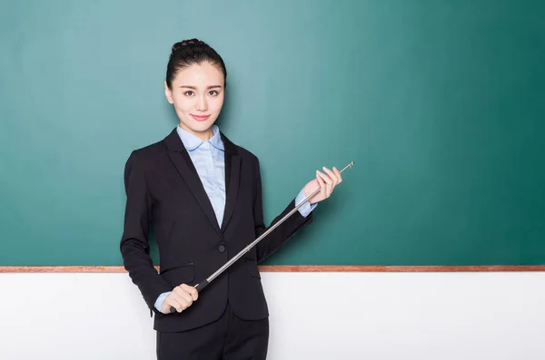 Portrait of female teacher pointing to chalkboard. — Stock Photo, Image
