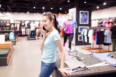 Alışveriş merkezindeki güzel Çinli kız kendi kıyafetlerini seçiyor.