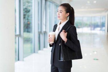 Siyah takım elbiseli güzel bir kız, ofis binasında duruyor.