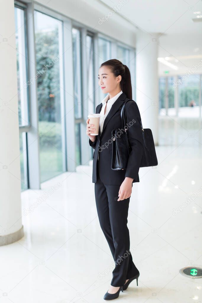 pretty girl wearing a black suit, standing in office building