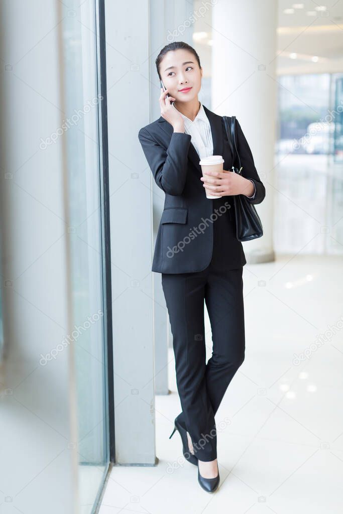 pretty girl wearing a black suit, standing in office building