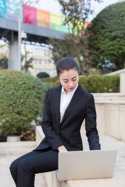 Güzel kız dışarıda dizüstü bilgisayar kullanan bir devlet memuru.