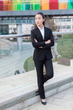 Güzel Çinli kız, iş elbisesi giymiş, köprüde duruyor.