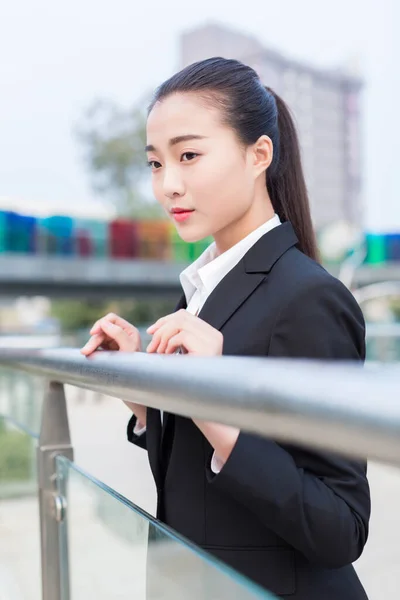 かなり中国人の女の子が橋の上に立っている指輪のビジネス服を着て ロイヤリティフリーのストック写真