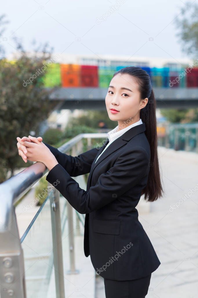 pretty chinese girl, dressed  sring business attire standing on the bridge