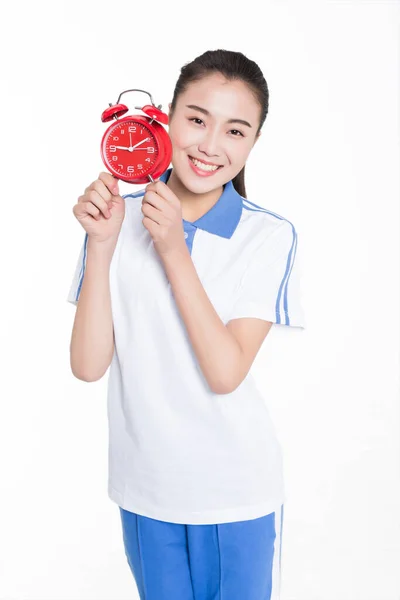Estudiante Femenina China Vistiendo Uniforme Azul Sosteniendo Despertador Rojo Fotos de stock libres de derechos