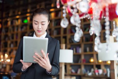 Kafede tablet kullanan beyaz yakalı bir kız.