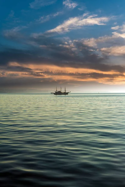 Escena minimalista de mar y barco, bajo el cielo de colores del atardecer —  Fotos de Stock