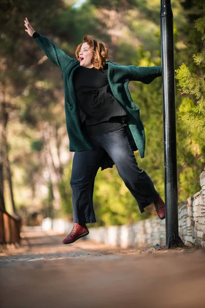 Jumping, Woman in the park, looking at left and smilling, full b