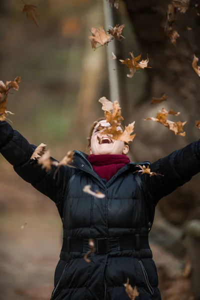 Femme jetant des feuilles sur l'air, profitant de la vie, plans en plein air — Photo