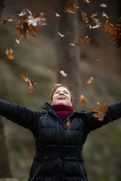 Femme jetant des feuilles sur l'air, profitant de la vie, plans en plein air — Photo