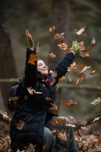 Femme jetant des feuilles sur l'air, profitant de la vie, plans en plein air — Photo