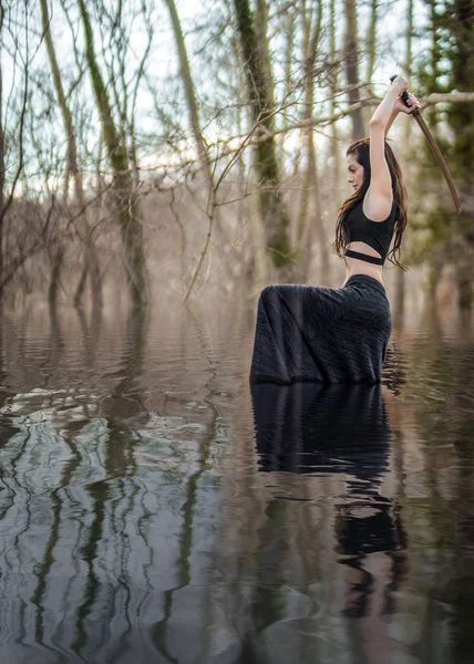 Femme guerrière tenant une épée Katana dans les eaux du lac Mystic Images De Stock Libres De Droits
