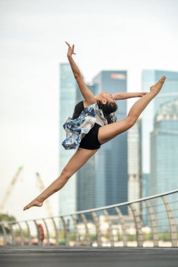 Canlı yayında dans... Güzel genç dansçı poz, perfoming mükemmel atlama, gökdelenlerin arka plan 