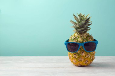 Ananas ahşap masa üzerinde güneş gözlüğü ile