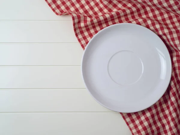 Kırmızı ekose desenli masa örtüsü üzerinde beyaz tabak — Stok fotoğraf
