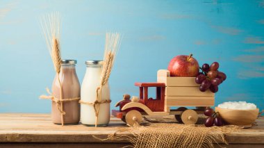 Süt, çikolatalı süt şişeleri ve oyuncak kamyon üzerinde ahşap masa meyve ile. Yahudi tatil shavuot kavramı.