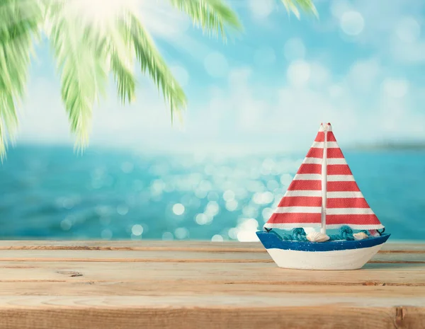 Summer vacation concept with boat decor over bokeh palm tree and tropical sea beach background