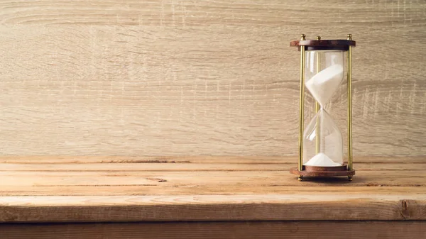 Reloj de arena sobre mesa de madera — Foto de Stock